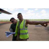 Un soldat du détachement de transit interarmées (DéTIA) échange avec un convoyeur espagnol pour le chargement de matériel à bord d'un avion hercules C-130 sur l'aéroport de Bamako-Sénou, au Mali.