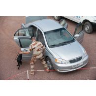 Un fusilier commando de l'Air fouille un véhicule avec son chien au poste de sécurité principal du camp Adji Kosseï à N'Djamena, au Tchad.