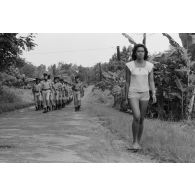 Défilé des troupes à l'issue de la crémonie de remise de la fourragère à de jeunes marsouins du régiment d’infanterie de marine du Pacifique - Polynésie (RIMAP-P) à Taravao. Une femme marche sur la route.