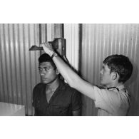 Examen médical des élèves gradés (PEG) du 57e bataillon de commandement et de soutien du Pacifique (57e BCSP) au camp d'Arue. Mesure de la taille sous la toise.