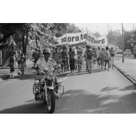 A Papeete, un motard de la police municipale encadre une manifestation antinucléaire dont les participants portent une banderole énonçant  "ia ora te natura" (vive la nature).