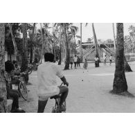 Installations sportives en zone Vie sur l'atoll de Moruroa (Mururoa). Partie de pétanque. En arrière-plan, une plateforme de secours pour les personnels en cas d'alerte à la vague, lors des tirs d'essais nucléaires.