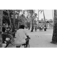 Installations sportives en zone Vie sur l'atoll de Moruroa (Mururoa). Partie de pétanque. En arrière-plan, une plateforme de secours pour les personnels en cas d'alerte à la vague, lors des tirs d'essais nucléaires.