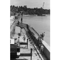 A Moruroa, édification d'un mur de protection contre les raz de marée par les légionnaires du 5e régiment mixte du Pacifique (5e RMP). Levage par une grue PPM.