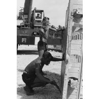 A Moruroa, édification d'un mur de protection contre les raz de marée par le 5e régiment mixte du Pacifique (5e RMP). Des légionnaires, masse en main, décapent un élément de coffrage.