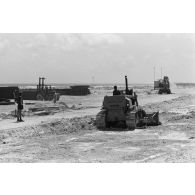 A Moruroa, édification d'un mur de protection contre les raz de marée par les légionnaires du 5e régiment mixte du Pacifique (5e RMP). Un engin Caterpillar terrasse la zone.