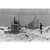 A Moruroa, édification d'un mur de protection contre les raz de marée par les légionnaires du 5e régiment mixte du Pacifique (5e RMP). Un engin Caterpillar terrasse la zone.