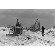 A Moruroa, édification d'un mur de protection contre les raz de marée par les légionnaires du 5e régiment mixte du Pacifique (5e RMP). Un engin Caterpillar terrasse la zone.