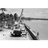 A Moruroa, édification d'un mur de protection contre les raz de marée par les légionnaires du 5e régiment mixte du Pacifique (5e RMP). Levage par une grue PPM.