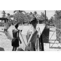 A Moruroa, édification d'un mur de protection contre les raz de marée par le 5e régiment mixte du Pacifique (5e RMP). Des légionnaires décapent les résidus de béton sur la paroi métallique d'un élément de coffrage.