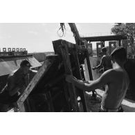 A Moruroa, édification d'un mur de protection contre les raz de marée par les légionnaires du 5e régiment mixte du Pacifique (5e RMP). Manipulation d'un élément de coffrage.