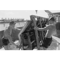 A Moruroa, édification d'un mur de protection contre les raz de marée par les légionnaires du 5e régiment mixte du Pacifique (5e RMP). Manipulation d'un élément de coffrage.