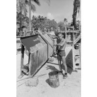 A Moruroa, édification d'un mur de protection contre les raz de marée par le 5e régiment mixte du Pacifique (5e RMP). Un légionnaire applique un enduit sur la paroi métallique d'un élément de coffrage, son collègue décape les résidus de béton.