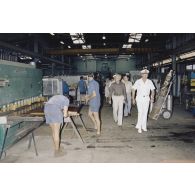 Arrivée à la direction des constructions et armes navales (DCAN) des membres de la commission de la Défense nationale. Visite d'atelier avec l'ingénieur en chef de l’armement (ICA) Duval.
