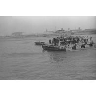 Des soldats et des chevaux traversent le cours d’eau à bord d’une barge.