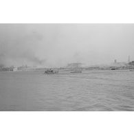 Des soldats et des chevaux traversent le cours d’eau à bord d’une barge.