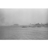 Des soldats et des chevaux traversent le cours d’eau à bord d’une barge.