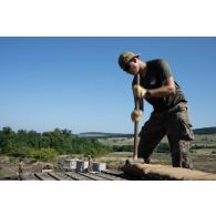 Un sapeur du 19e régiment du génie (RG) dépose des sacs à terre pour la conception d'un poste de combat dans une tranchée à Cincu, en Roumanie.