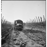 Un camion GMC progresse entre des obstacles bordant une route non carrossée.
