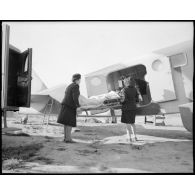 Transport d'un blessé à bord d'un avion sanitaire avec l'aide des infirmières de l'air.