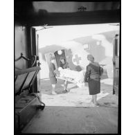 Transport d'un blessé à bord d'un avion sanitaire avec l'aide des infirmières de l'air.