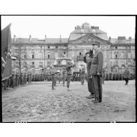Au cours d'une cérémonie sur la place du château des Rohan à Saverne, le général de Gaulle et le lieutenant général américain Jacob Devers, commandant le 6e groupe d'armées, saluent les emblèmes.<br><br>