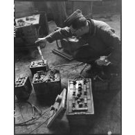 Contrôle au densimètre de batteries de véhicules dans l'atelier de réparation automobile de la compagnie mixte de transmissions 97/84 de la 2e division blindée (2e DB).