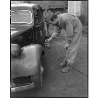 Peinture au pistolet de marquages sur une Citroën traction avant dans l'atelier de réparation automobile de la compagnie mixte de transmissions 97/84 de la 2e division blindée (2e DB).