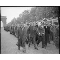 Des déportés politiques s'éloignent de l'Arc de Triomphe à l'issue d'une cérémonie de ravivage de la flamme sur la tombe du Soldat inconnu.
