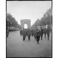 Des déportés politiques s'éloignent de l'Arc de Triomphe à l'issue d'une cérémonie de ravivage de la flamme sur la tombe du Soldat inconnu.