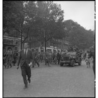 A l'occasion de la visite du général Eisenhower à Paris, les Parisiens se mêlent aux troupes américaines sur les Champs-Elysées.
