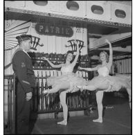 Des danseuses d'un corps de ballet font des exercices "à la barre" dans l'armurerie du porte-avions Béarn à bord duquel elles participent à un spectacle pour la soirée, la veille de Noël.