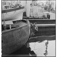 Un marin repeint la coque à la poupe d'un chalutier.