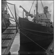 Un chalutier réquisitionné et armé par la Marine nationale accoste dans un port.