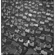 Vue en plongée sur l'équipage du porte-avions Béarn rassemblé dans une salle à l'occasion d'un spectacle donné sur le navire le soir, la veille de Noël.