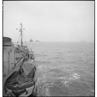Un torpilleur, le Bouclier ou le Flore, escorte et ouvre la voie à un convoi de cargos de la marine marchande.