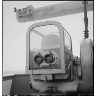 Un marin est au poste de conduite ou de direction de tir d'un canon du croiseur Strasbourg, naviguant au large de l'Afrique occidentale française (AOF).