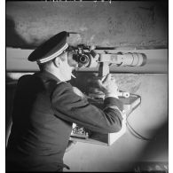 Un enseigne de vaisseau est au poste de veille optique dans le blockhaus, à bord du torpilleur léger Branlebas.