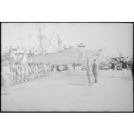 Les autorités militaires saluent le drapeau du 1er régiment de tirailleurs algériens (1er RTA) sur un quai du port d'Alger.