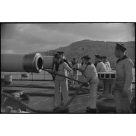 Ecouvillonnage d'un canon d'artillerie navale à bord d'un croiseur, probablement le croiseur lourd Duquesne.