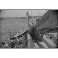 Une tente de camouflage est dressée sur la plage arrière d'un croiseur à quai.