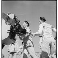 Des canonniers chargent un obus dans le fût d'un canon à bord du torpilleur Simoun.