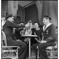 Des marins du torpilleur Simoun, descendus à terre, sont attablés à la terrasse d'un café.