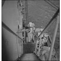 Déchargement de caisses de vivres par une échelle de coupée à bord d'un navire au mouillage dans la rade de Brest.<br>Cette photographie est en fait la photographie MARINE 101-1081.