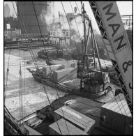 Dans le port de New-York pris par les glaces, des chalands transportent des caisses contenant des avions destinés aux Alliés, qui vont être chargées sur des cargos.