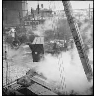 Dans le port de New-York pris par les glaces, des caisses qui contiennent des avions destinés aux Alliés sont chargées à bord d'un cargo.