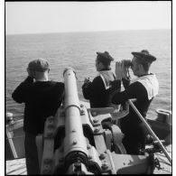 Des canonniers observent l'horizon depuis la plate-forme sur laquelle se trouve le canon de 90 mm du pétrolier Bourgogne.