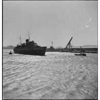 Le paquebot transport de troupes Ville d'Alger est pris en charge par des remorqueurs dans le port de Marseille.