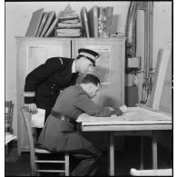 Un capitaine de corvette et un commandant français sont penchés sur une carte au poste de commandement de l'amiral Abrial à Dunkerque.