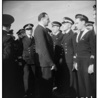 Louis Jacquinot, ministre de la Marine, passe en revue des officiers, officiers mariniers et marins lors d'une cérémonie à bord d'un bâtiment.